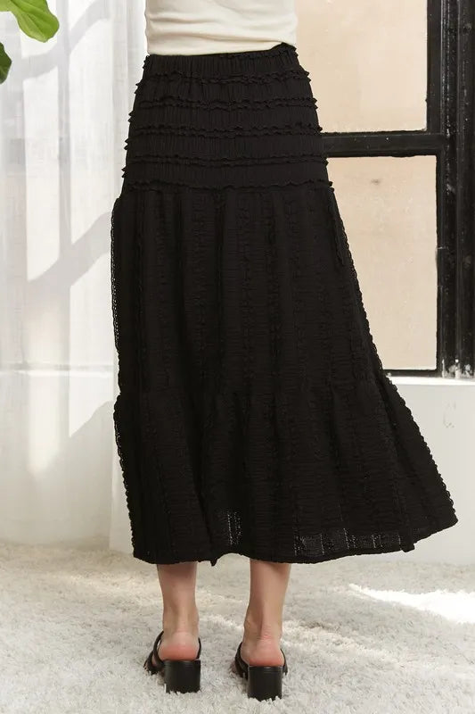 Black ADORA elastic waistband tiered midi skirt by Trendsi, featuring a flowy, layered design and comfortable elastic waist.