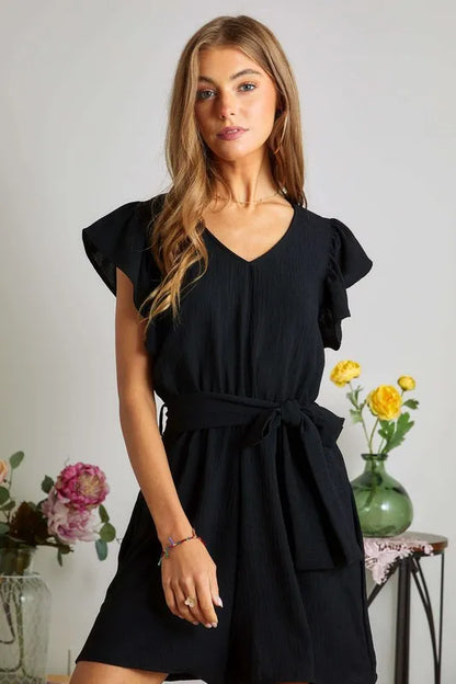 Black ADORA Ruffle Sleeves Romper with Pockets by Trendsi, featuring ruffled sleeves and a comfortable, stylish design.