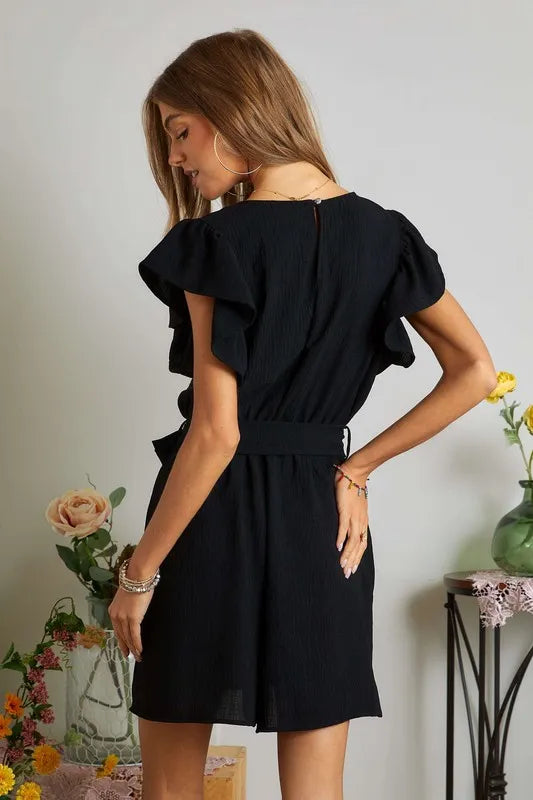 Black ADORA Ruffle Sleeves Romper by Trendsi featuring ruffled sleeves and side pockets, displayed on a neutral background.
