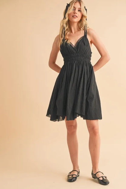 Black Aemi+Co lace detail mini cami dress by Trendsi, featuring delicate lace accents and a fitted sleeveless design.
