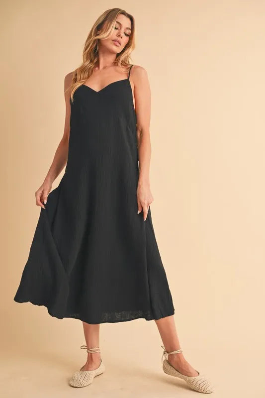 Black Aemi+Co side button midi cami dress from Trendsi, featuring a fitted silhouette, side buttons, and spaghetti straps.