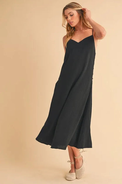 Black Aemi+Co side button midi cami dress by Trendsi, featuring a sleek silhouette and adjustable straps, perfect for casual occasions.
