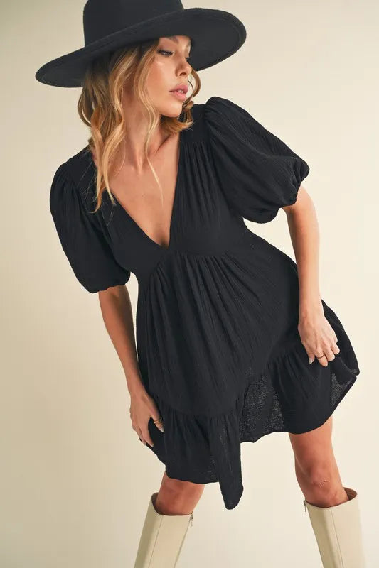 Black Aemi+Co tied-back ruffled short sleeve mini dress, stylish and feminine, featuring a flirty ruffled hem and back tie detail.