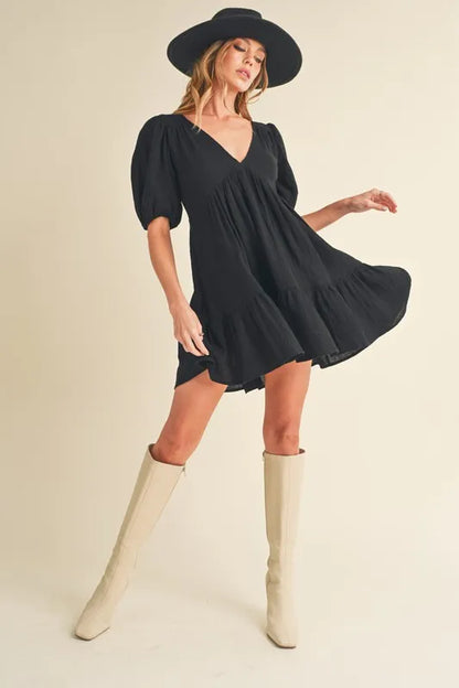 Black Aemi+Co tied-back ruffled short sleeve mini dress, showcasing a stylish design with a gathered back detail.
