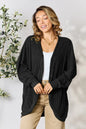 Black Trendsi Basic Bae full-size ribbed cocoon cardigan draped on a hanger, showcasing its relaxed fit and textured knit fabric.
