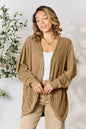 Black Basic Bae Full Size Ribbed Cocoon Cardigan by Trendsi, displayed on a hanger with a relaxed fit and textured ribbed fabric.