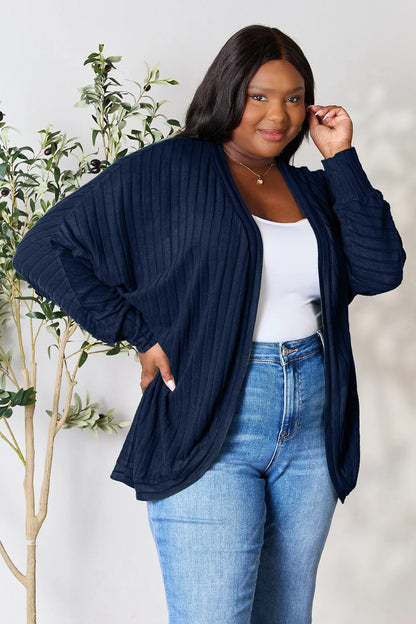Black Trendsi Basic Bae full-size ribbed cocoon cardigan draped on a hanger, showcasing its relaxed fit and textured knit fabric.