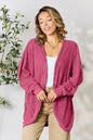 Black Trendsi Basic Bae full-size ribbed cocoon cardigan draped on a hanger, showcasing its relaxed fit and textured knit fabric.