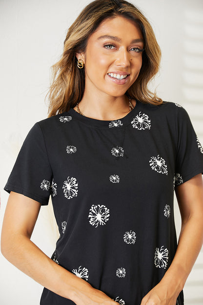 Black Trendsi Double Take Dandelion Print round neck T-shirt with colorful floral design on front.