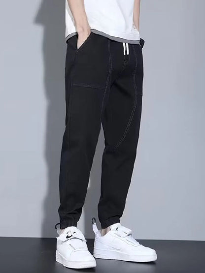Men's black full-size casual denim joggers from Trendsi, loose fit, comfortable plus-size denim pants on a model.