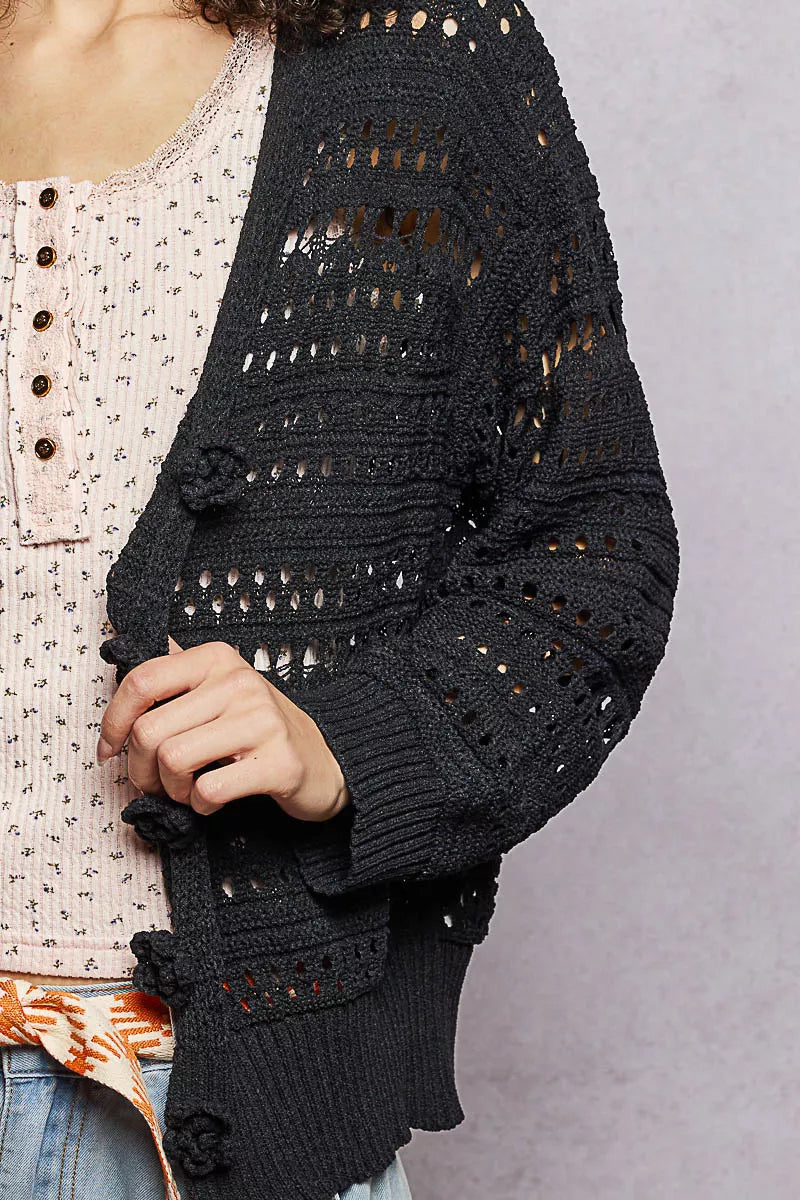 Black POL open-knit floral button cardigan by Trendsi, showing its lightweight, floral-patterned knit fabric and button closure.