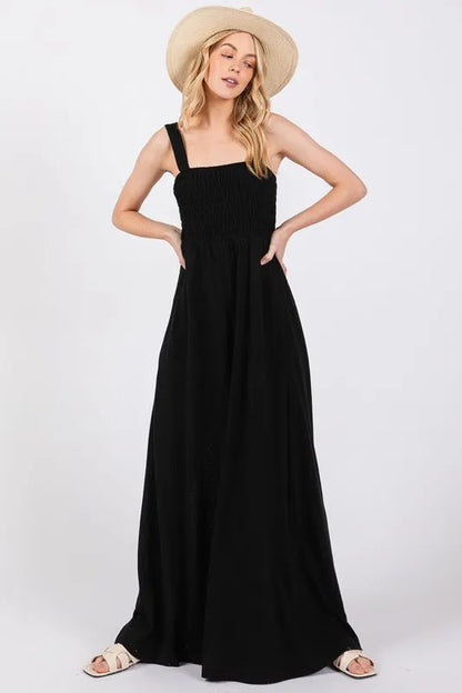Black Sage+Fig smocked flowy wide-leg jumpsuit with relaxed fit and adjustable straps, perfect for casual or summer wear.