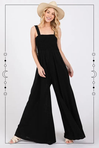 Black Sage+Fig smocked flowy wide-leg jumpsuit with adjustable straps and relaxed fit, perfect for casual or summer wear.