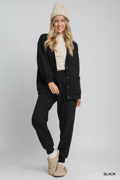 Black Umgee button-up jacquard cardigan with intricate knit pattern, styled open with long sleeves and a relaxed fit.