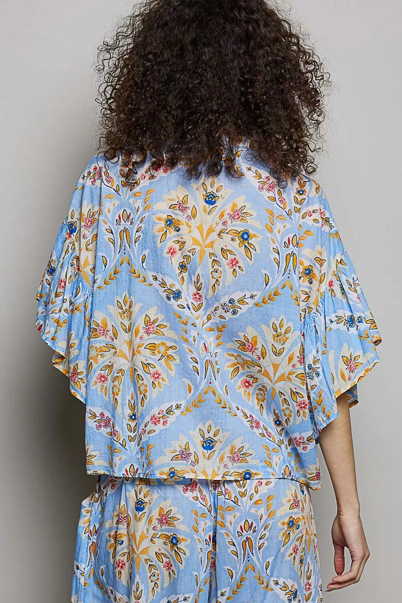 Blue floral printed woven ruffle sleeve shirt by Trendsi, featuring vibrant floral design and stylish ruffle sleeves.