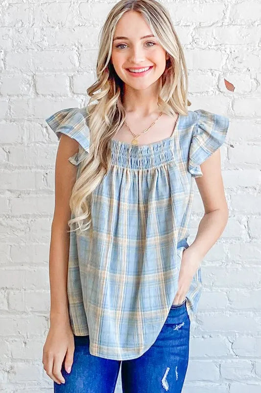 Blue plaid print baby doll top with smocked detail and ruffle accents from Trendsi's And The Why collection.