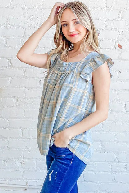 Blue plaid print baby doll top with smocked detail and ruffle accents from Trendsi's And The Why collection.