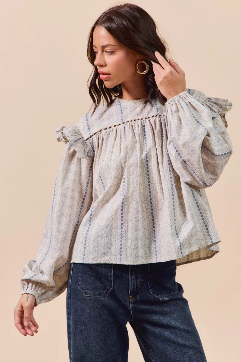 Blue floral cotton print ruffled long sleeve blouse by Trendsi with feminine design and detailed ruffle accents.