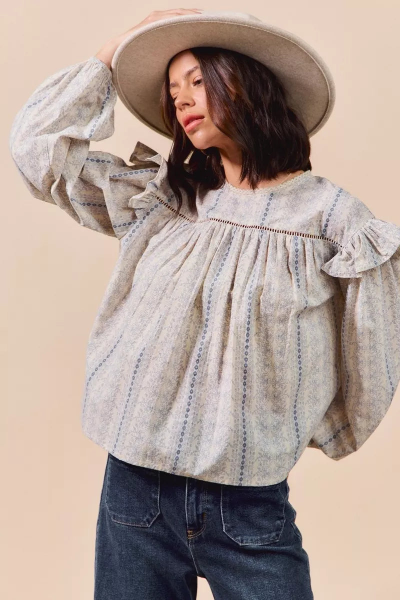 Blue floral cotton print ruffled long sleeve blouse by Trendsi, featuring feminine ruffle details and a comfortable cotton fabric.