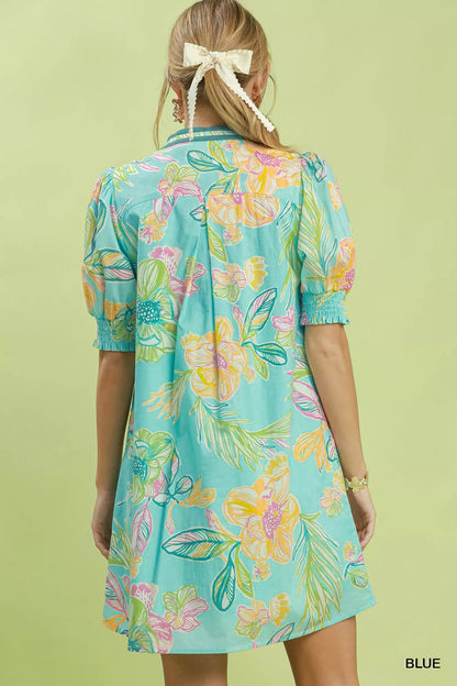 Blue Umgee botanical print dress with smocked cuffs, featuring a flowing design and floral pattern, styled for casual wear.