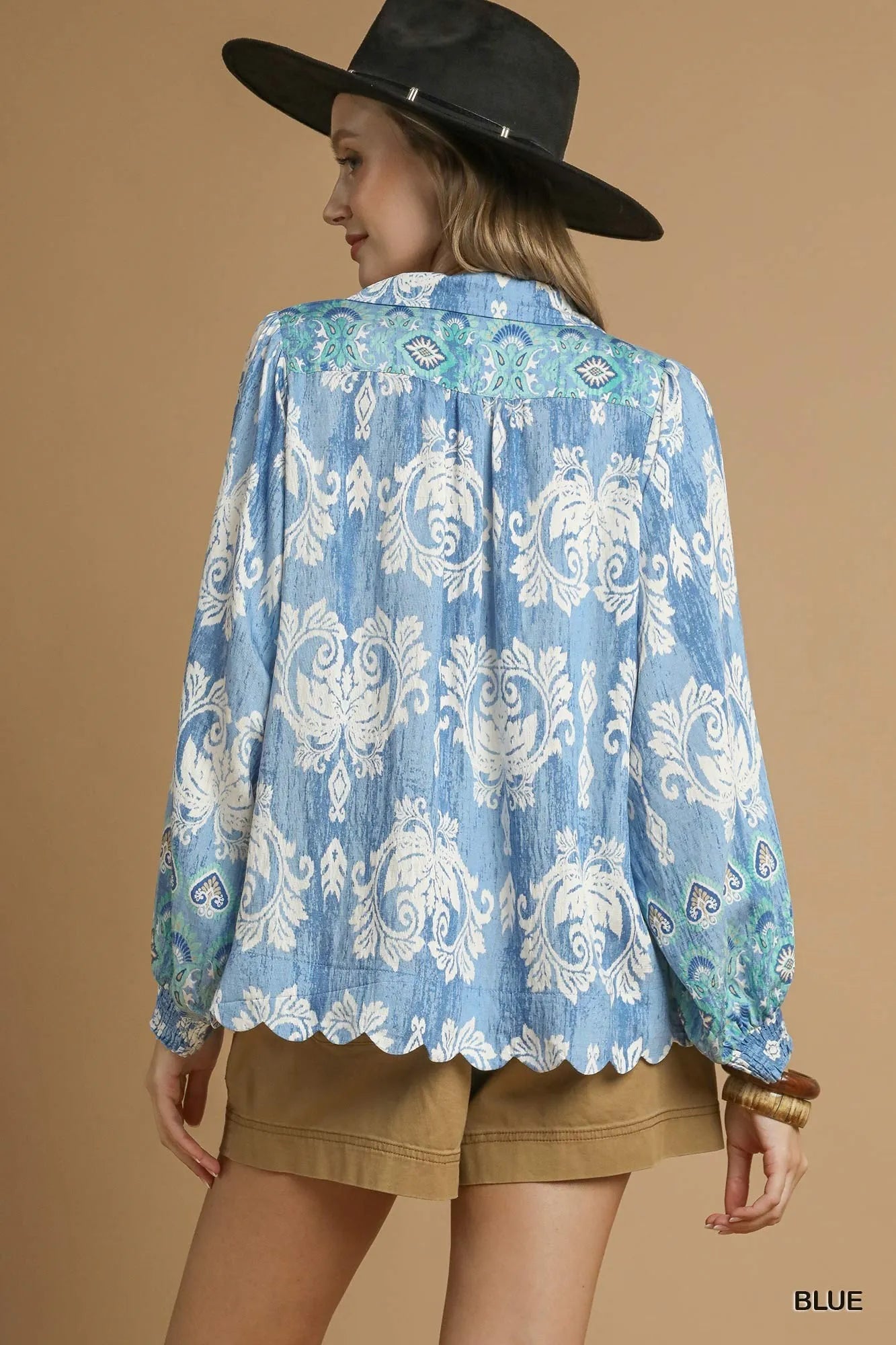 Blue Umgee printed long sleeve blouse with a relaxed fit and floral pattern, displayed on a hanger.