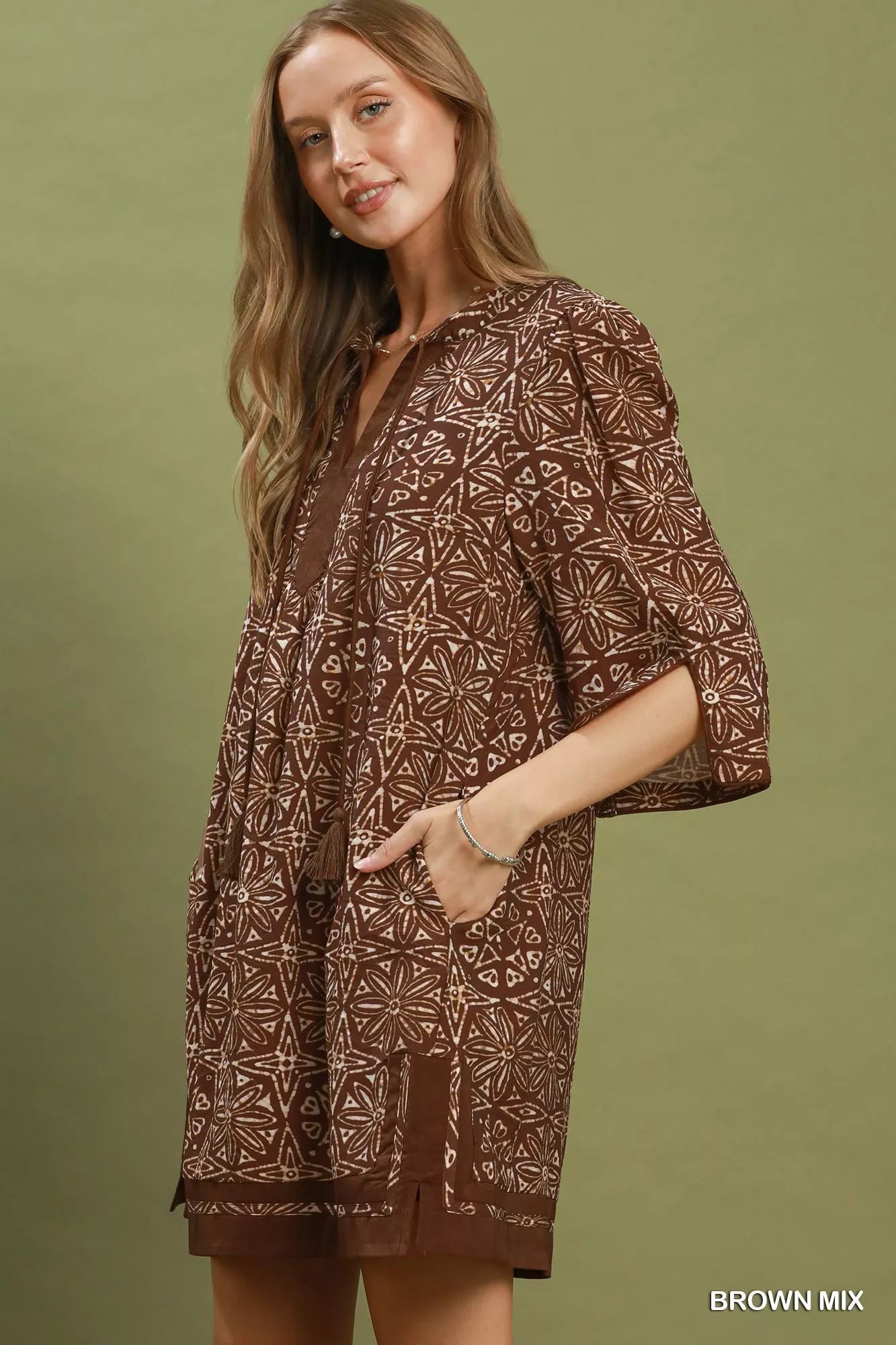 Brown Umgee geometric print tunic dress with V-neck and tassel details, featuring a relaxed fit and stylish design.