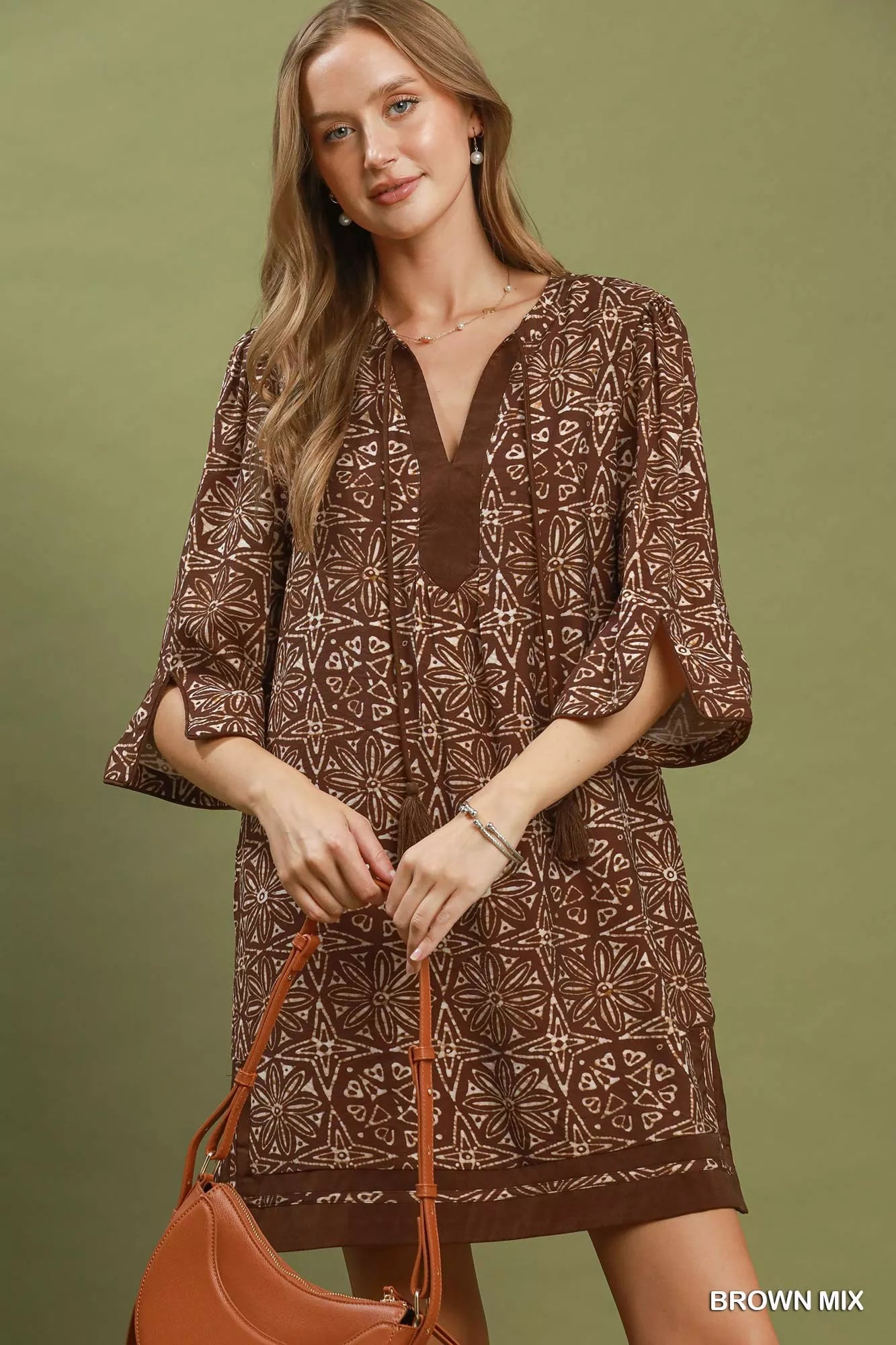 Brown Umgee geometric print tunic dress with V-neck and tassel details, featuring a relaxed fit and stylish design.