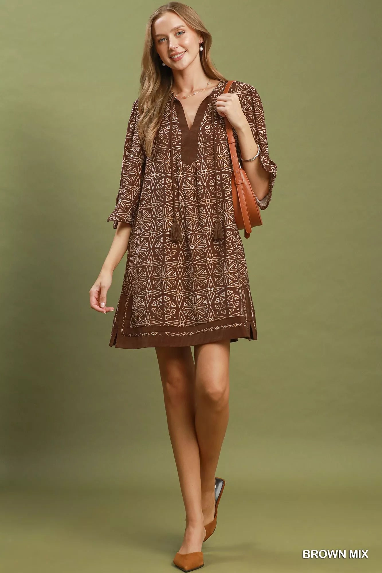 Brown Umgee geometric print tunic dress with V-neck and tassel details, featuring a relaxed fit and stylish design.