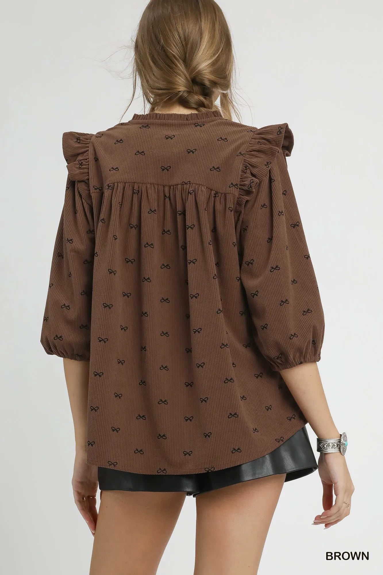 Brown Umgee bow print corduroy puff sleeve blouse with ruffled details, stylish and comfortable for casual or dressy occasions.
