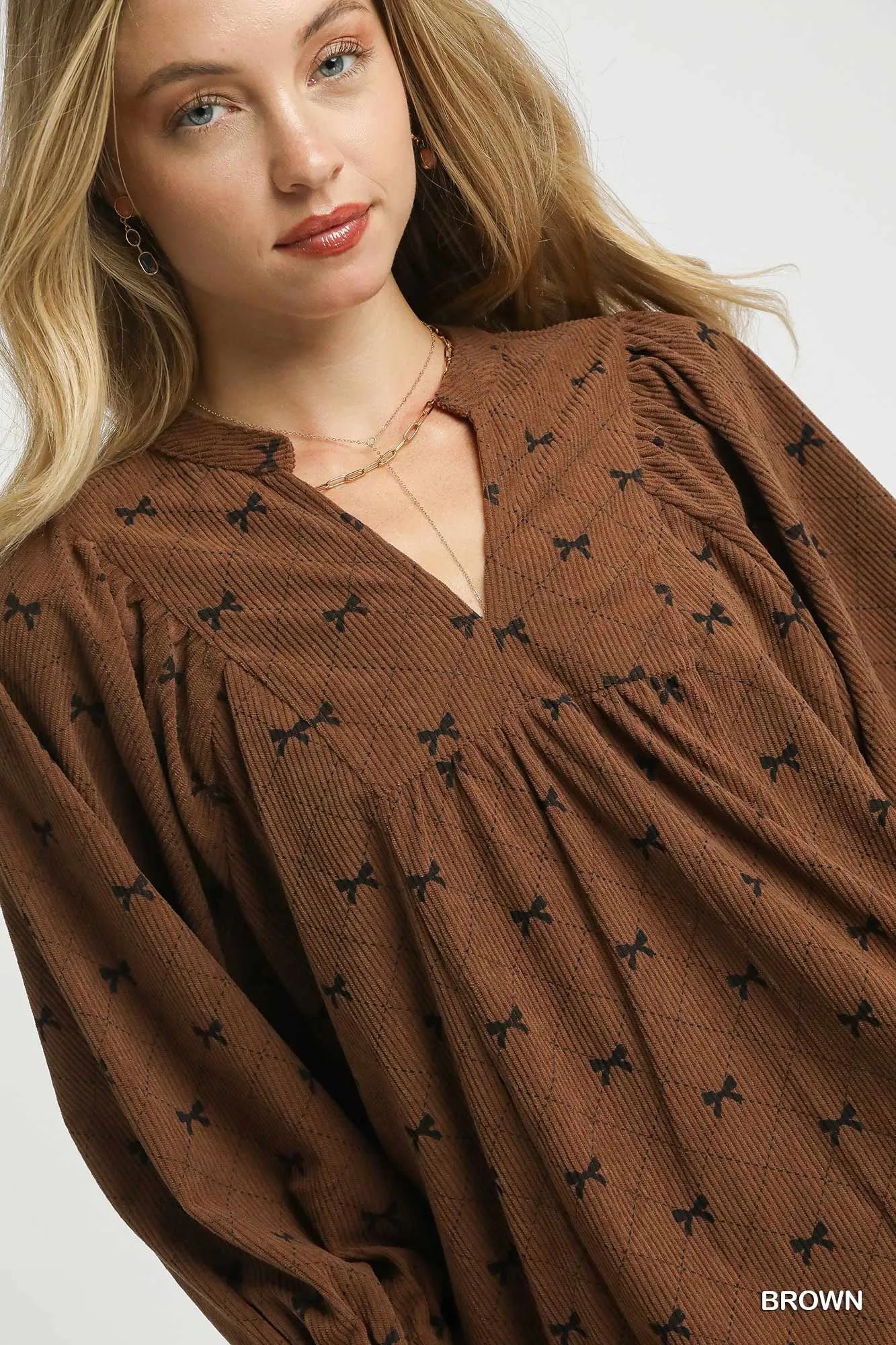 Brown Umgee corduroy blouse with bow print, balloon sleeves, and a relaxed fit, perfect for casual or stylish outfits.