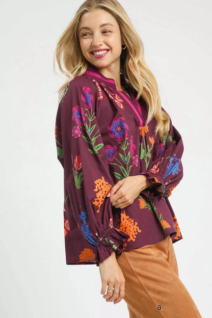 Burgundy floral print Umgee blouse with flounce sleeves, styled on a model showing the flowing fabric and vibrant pattern.