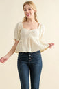 Cream textured and smocked top by Trendsi featuring a stylish, fitted design with intricate fabric details.
