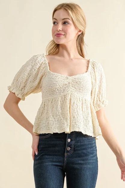 Cream textured and smocked top by Trendsi featuring a stylish, fitted design with intricate fabric details.