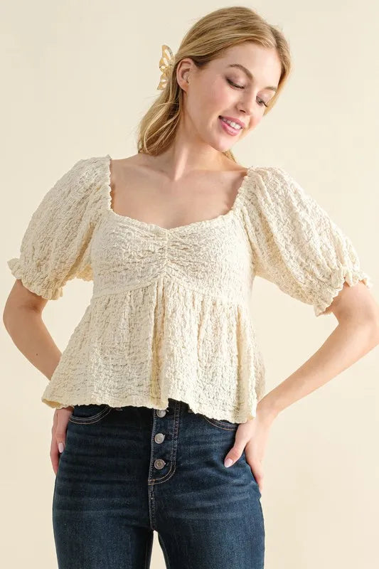 Cream-colored textured and smocked top by Trendsi, featuring a stylish and comfortable design with intricate details.