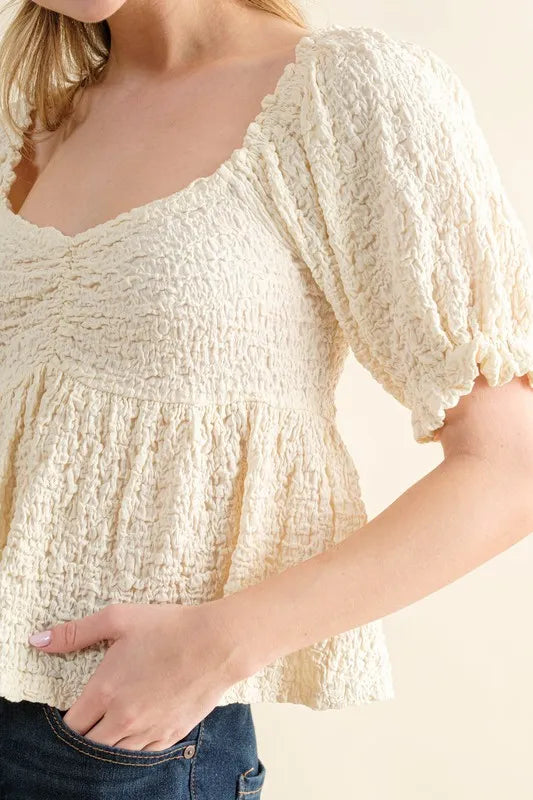 Cream textured and smocked top by Trendsi, featuring a stylish, fitted design with textured fabric and smocking details.