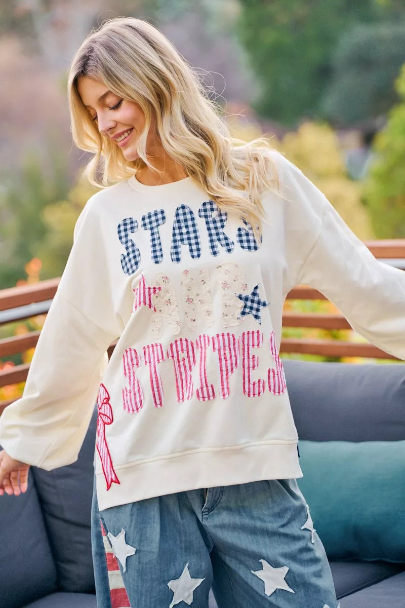 Cream sweatshirt with red, white, and blue stars and stripes patches on the front, featuring the BiBi 4th of July design by Trendsi.