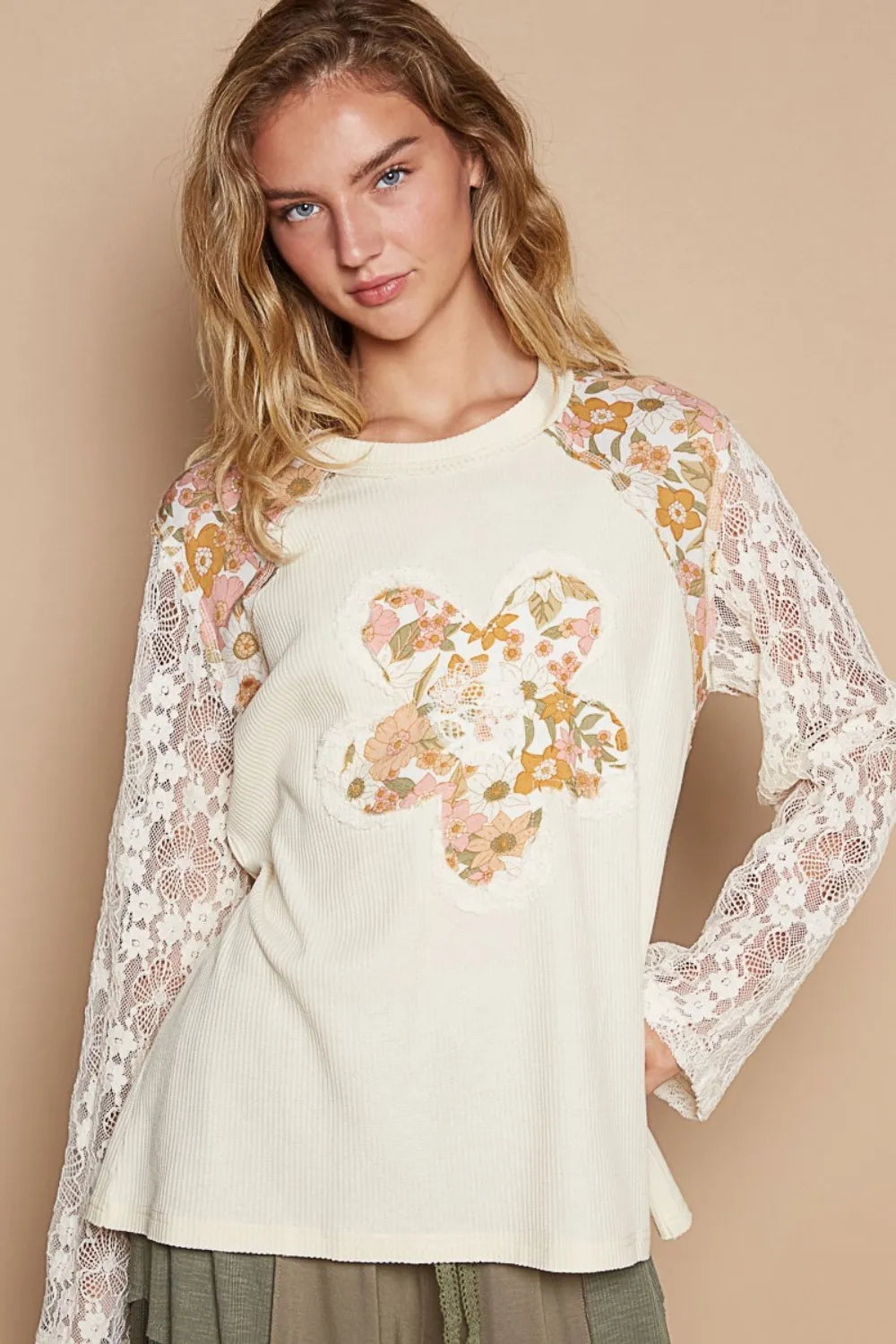 Cream knit top by Trendsi with lace sleeve details and floral patch accents, featuring a stylish and comfortable design.