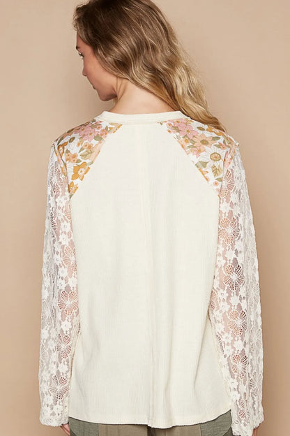 Cream knit top with lace sleeve details and floral patch accents from Trendsi, featuring a stylish, lightweight design.