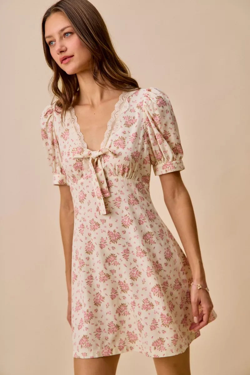 Cream floral lace-trimmed short sleeve mini dress by Trendsi, featuring delicate lace details and a fitted silhouette.