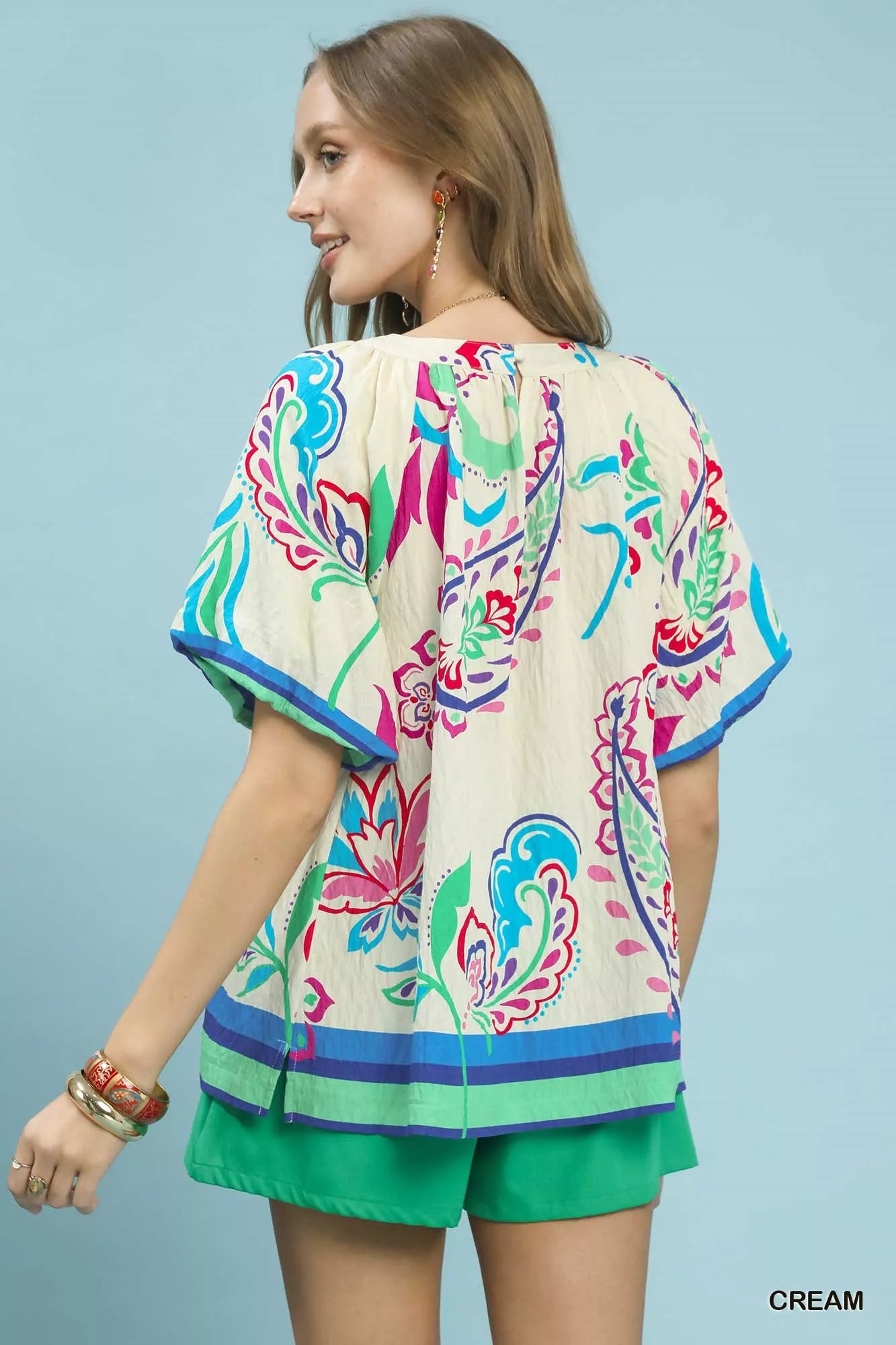 Cream Umgee border print puff sleeve blouse with ruffled details and relaxed fit, styled on a hanger.