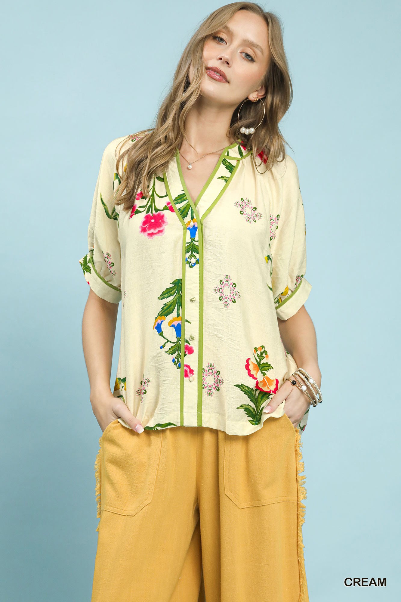 Cream Umgee botanical print blouse with contrast trim and button details, featuring a relaxed fit and stylish design.