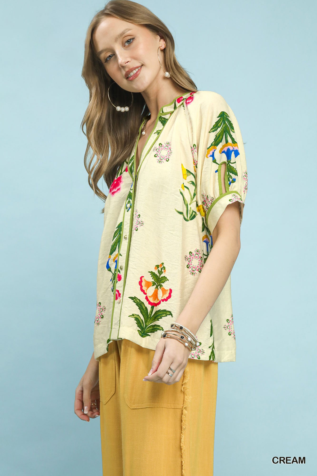 Cream Umgee botanical print blouse with contrast trim and button details, stylish and lightweight for a casual look.