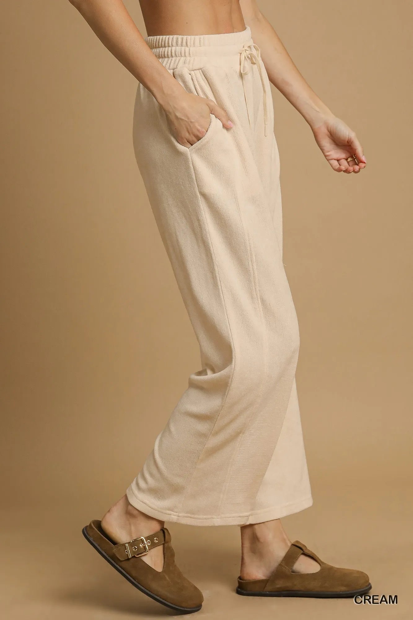 Cream Umgee drawstring wide-leg pants from Trendsi, featuring a relaxed fit and comfortable waistband, shown on a model.
