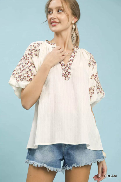 Cream Umgee embroidered sleeve top with contrast trim, featuring detailed embroidery and stylish design.