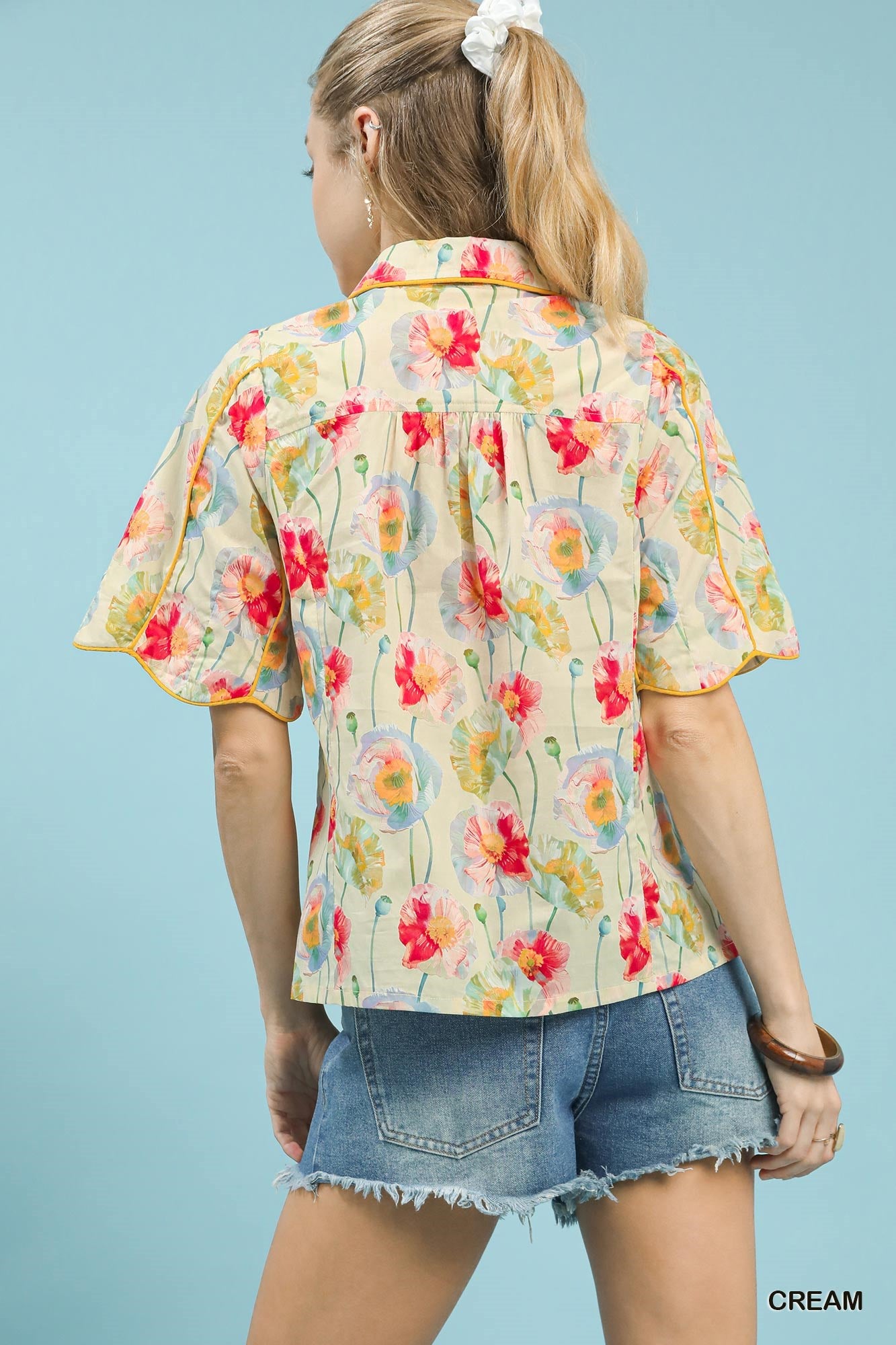 Cream floral print Umgee button-down blouse with flutter sleeves, displayed on a hanger.