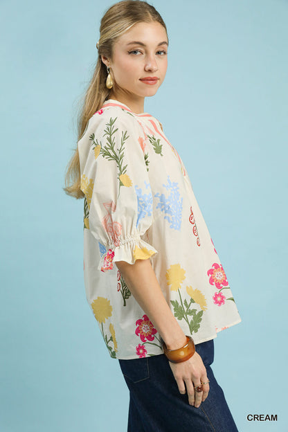 Cream floral split neck puff sleeve top by Umgee, shown on a model with ruffled sleeves and a relaxed fit.