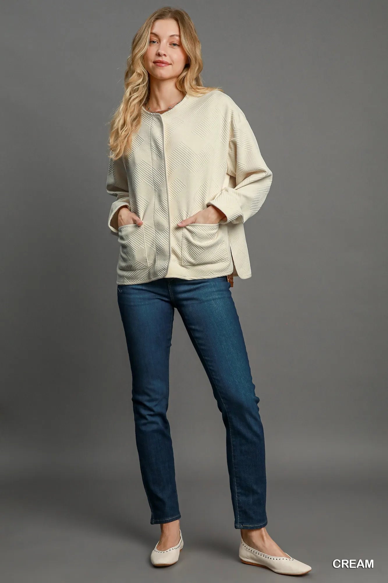 Cream Umgee textured jacquard jacket with long sleeves and a structured fit, showcasing intricate woven pattern and stylish design.