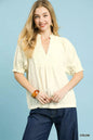 Cream Umgee textured smocked peasant top with long sleeves and a relaxed fit, styled on a hanger.