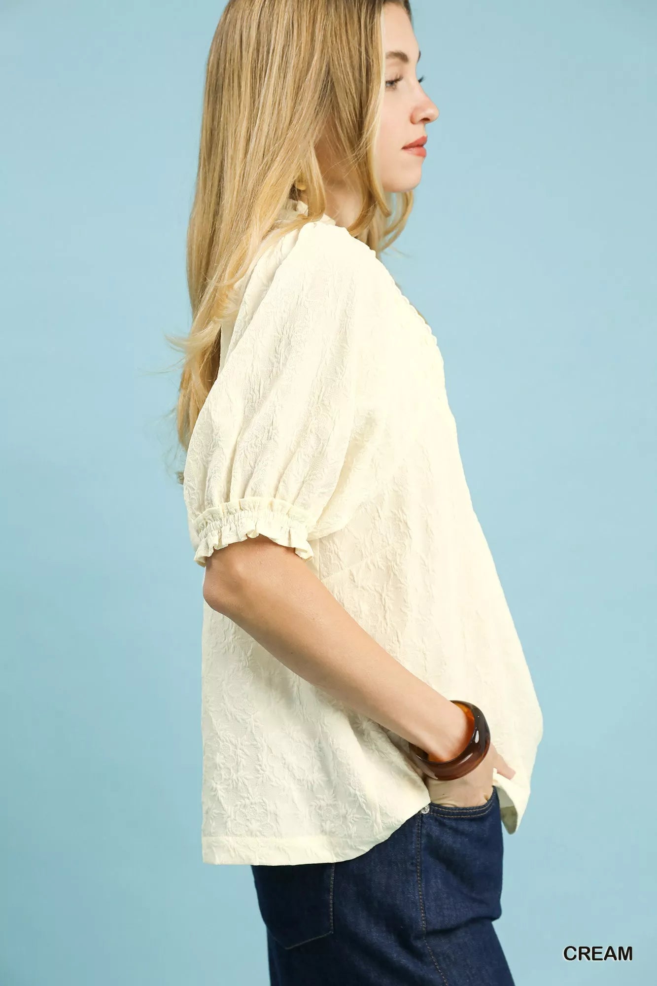 Cream Umgee textured smocked peasant top with long sleeves and ruffled neckline, displayed on a white background.