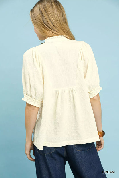Cream textured smocked peasant top from Umgee featuring a relaxed fit and detailed smocking, styled with long sleeves and a round neckline.
